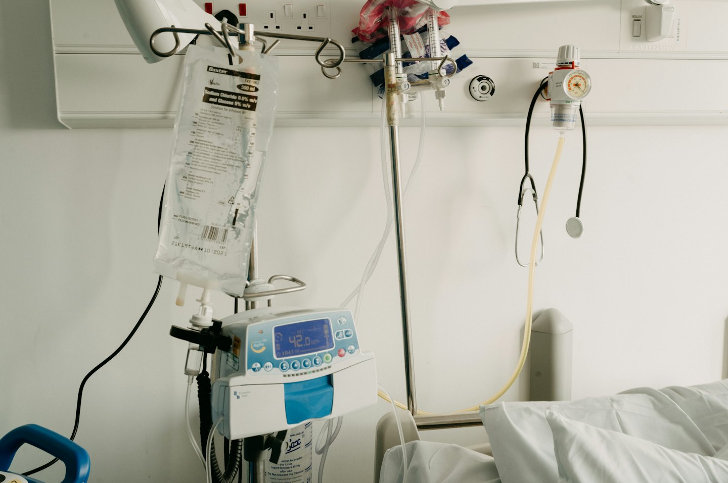 Bolsa de goteo intravenoso y equipo médico en una habitación de hospital.
