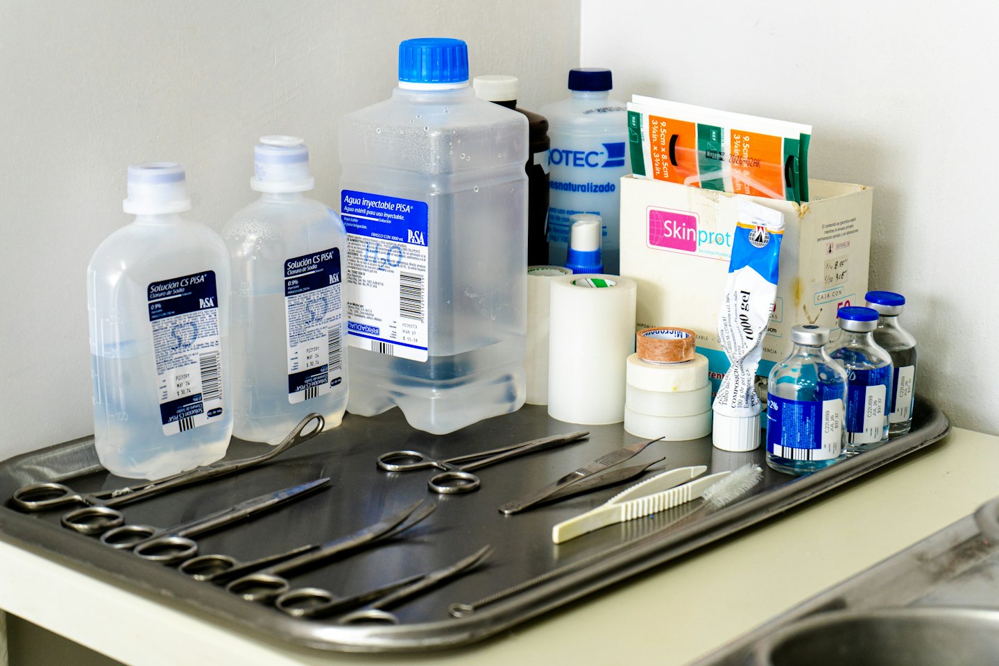 Suministros médicos e instrumentos quirúrgicos en una bandeja de acero.